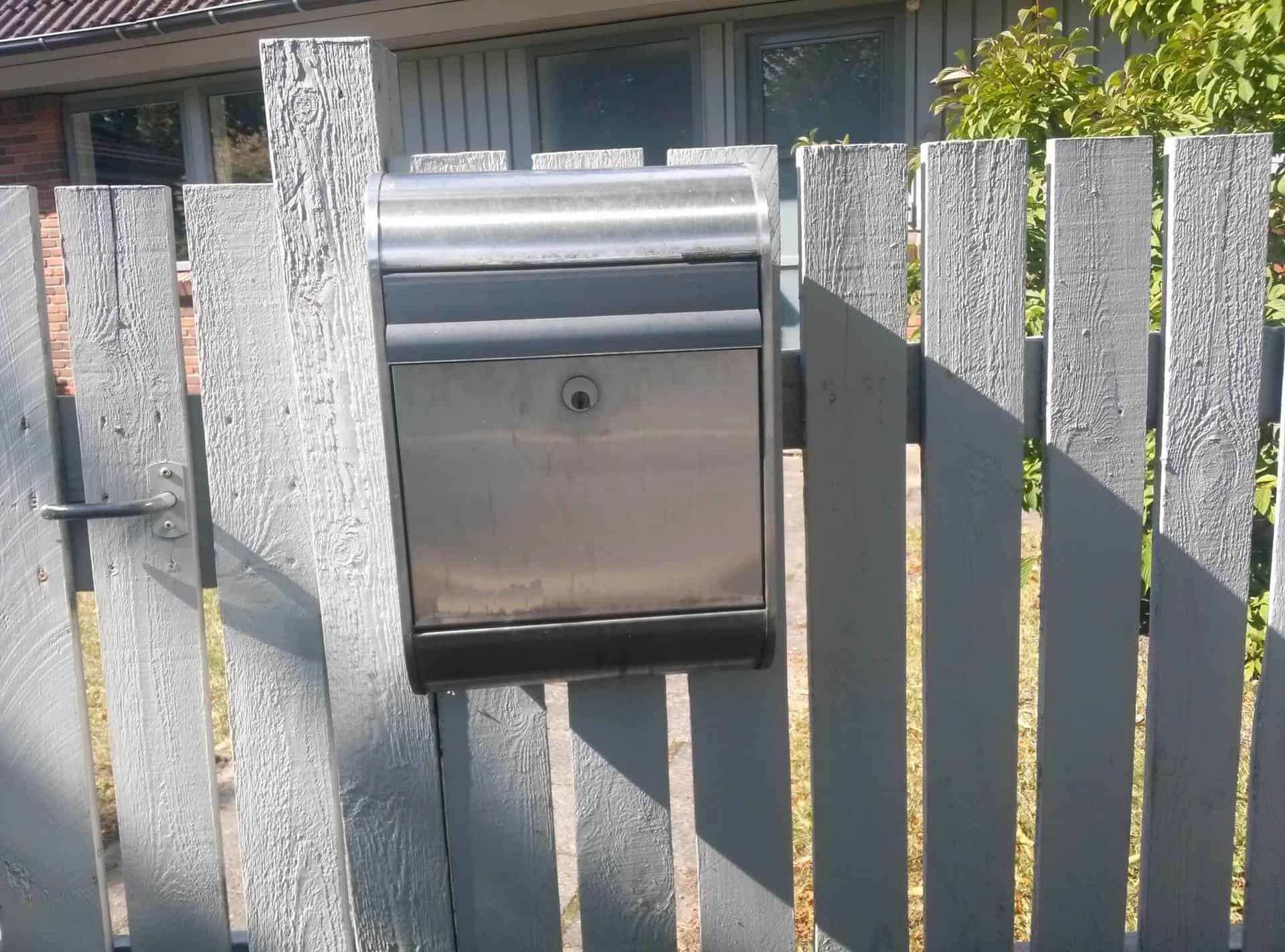 Grå postkasse på stakit
